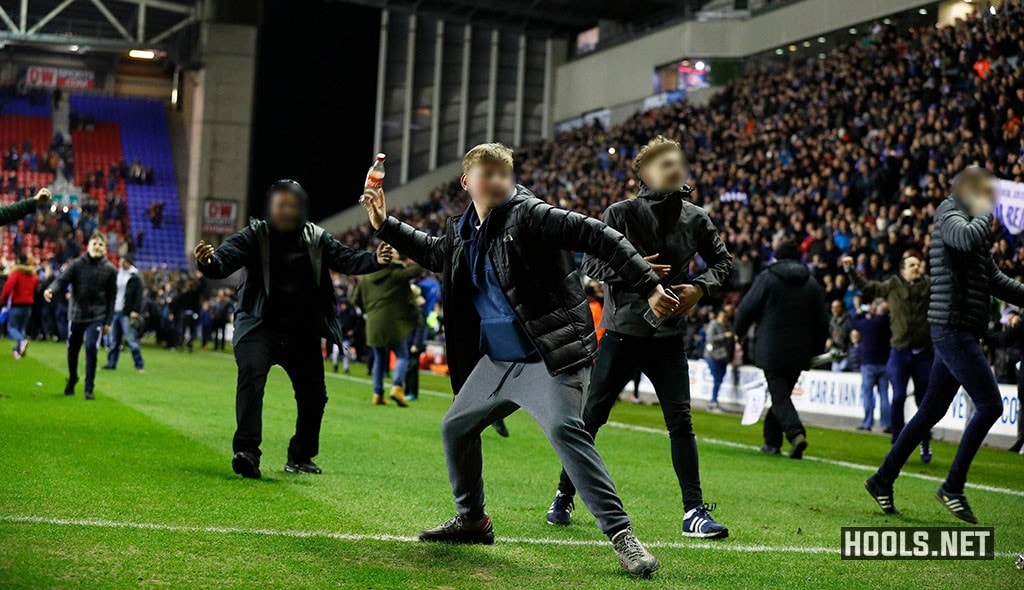 A Wigan fan throws a bottle towards supporters in the away end