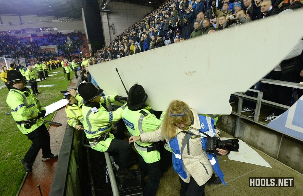 An advertising board thrown from the away section strikes cops
