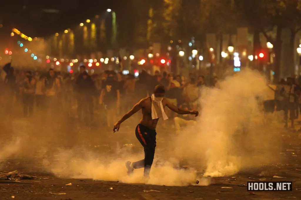 A man kicks a tear gas canister thrown by riot police during the clashes on the Champs Elysees.