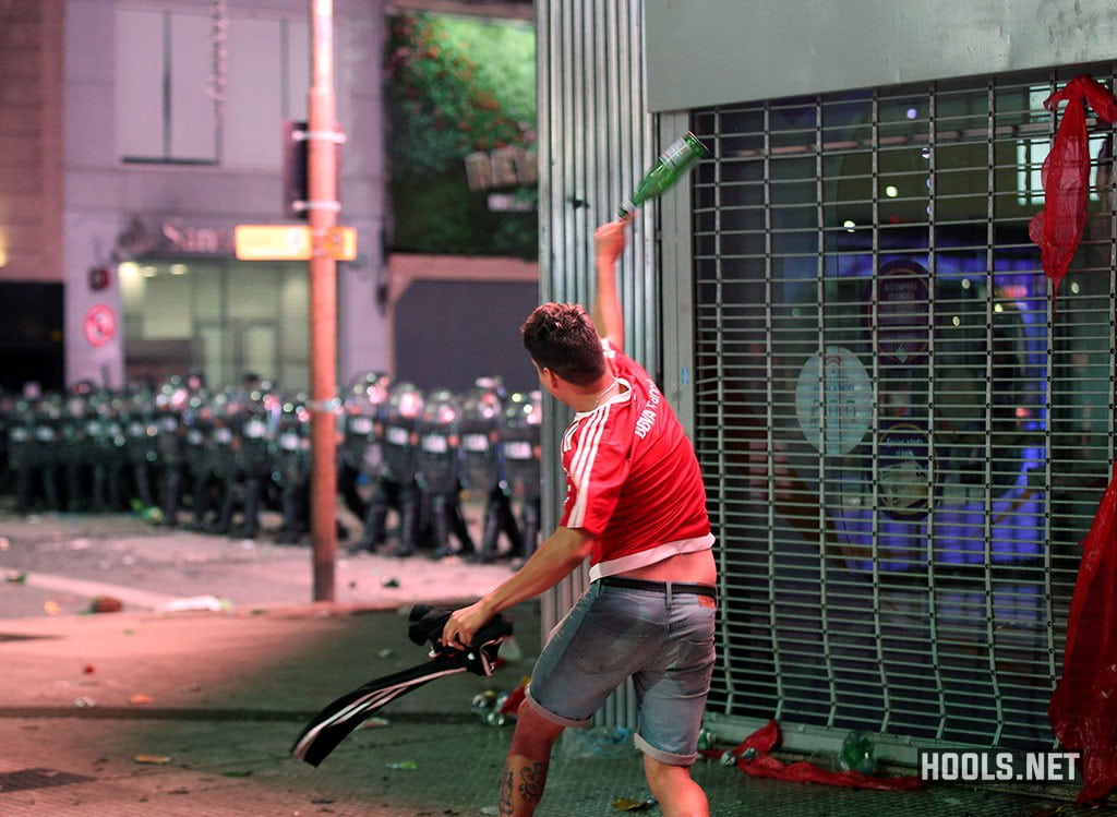 A Rive Plate fan throws a glass bottle at a line of riot cops