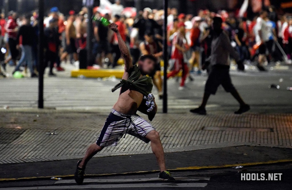 A River Plate fan throws a bottle towards riot cops