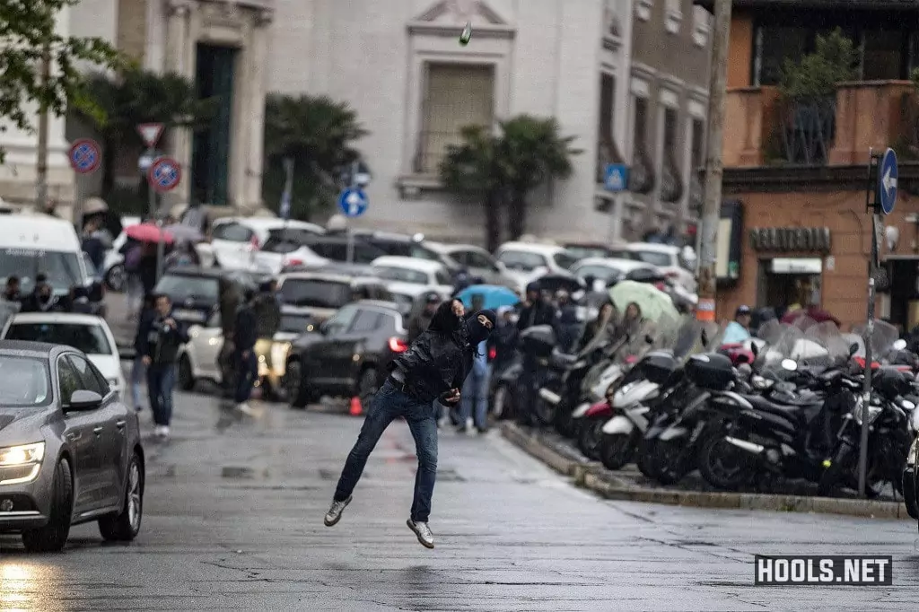 A Lazio hooligan throws a bottle towards riot police.