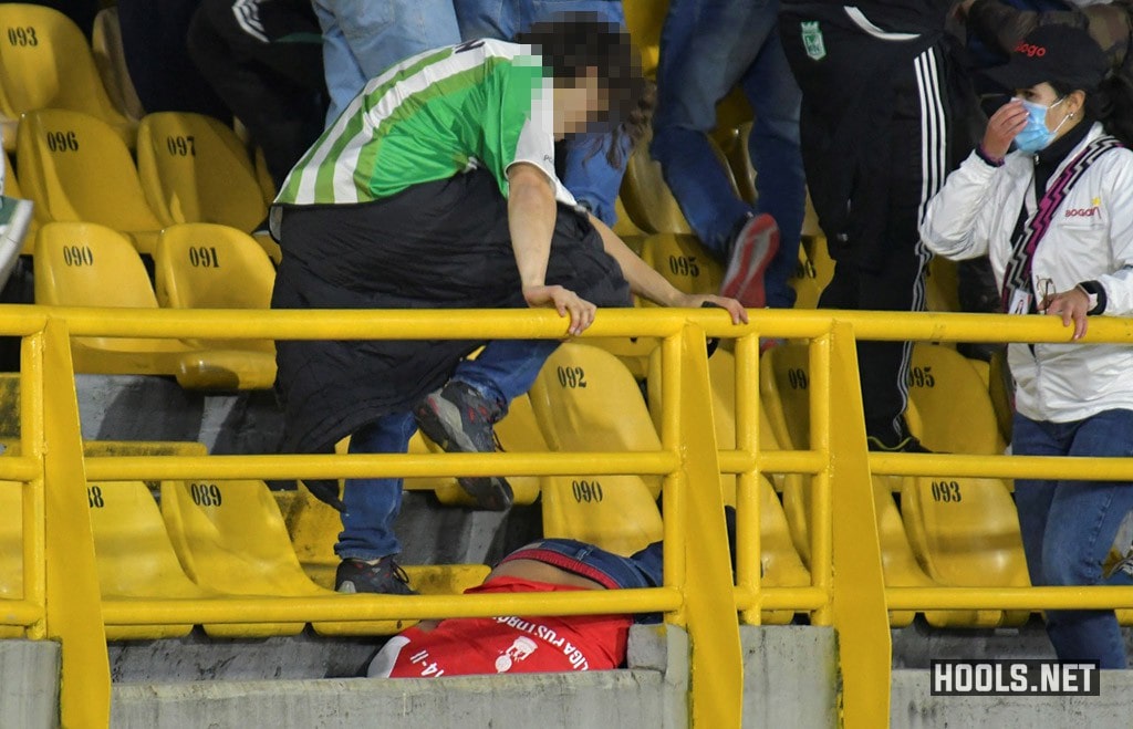 An Atletico Nacional fan stomps on a Santa Fe fan's head.