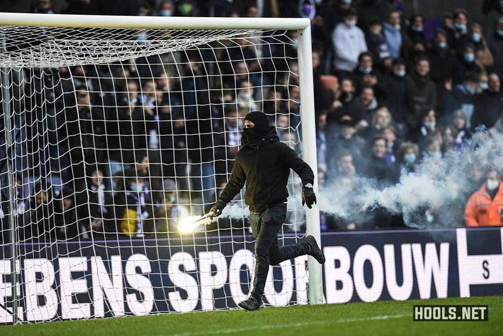 A Beerschot fan runs onto the pitch holding a flare during his side's match with Antwerp.